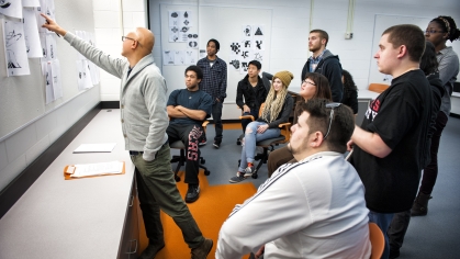 professor in classroom gesturing at papers as students watch