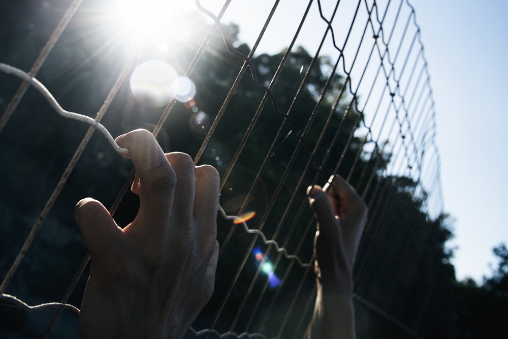 hands on a chain link fence