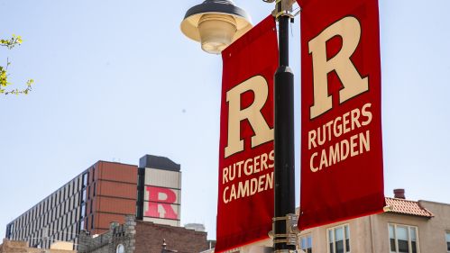 Rutgers Camden sign posts with the Student Housing building in the background.
