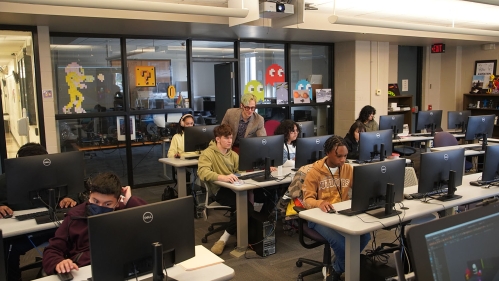 Animation teacher explains project to student as others work on their assignments