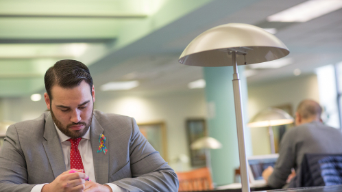 J.D. M.B.A. student studying at table with book and highlighter