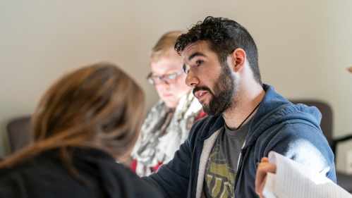 Students ask questions and hold notes.