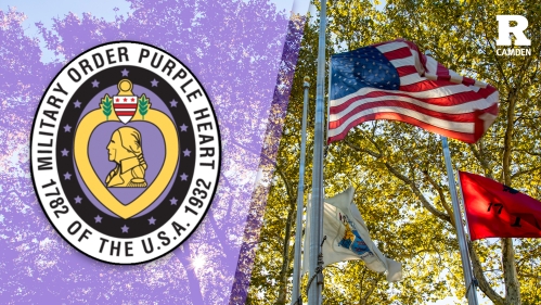 Purple Heart Day emblem and flag blowing in breeze