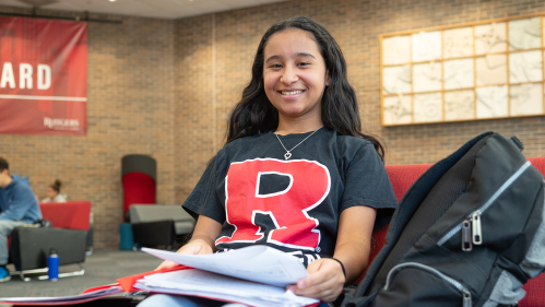Spanish student smiling with notes in student lounge