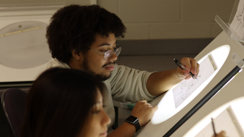 Two art students drawing using lightbox.