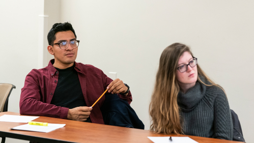 Students look on from thin desk with pencils, paper, and highlighter.