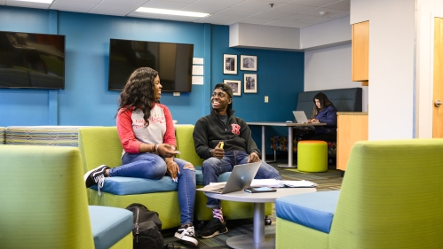 Female and male student talking in lounge area