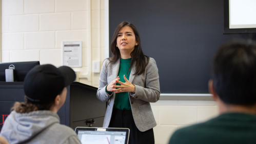 Professor in front of classroom with students at desks.
