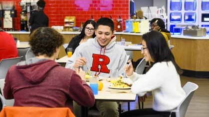 male and female Rutgers–Camden students sitting at a table, eating in a dining hall