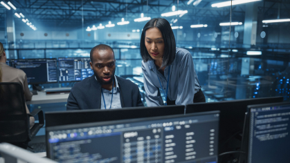 Black Male and Asian Female Engineer Collaborate on a Project in a Modern Data Center Office. Specialists Analyzing Complex Systems on Multiple Screens to Improve Cybersecurity and Performance