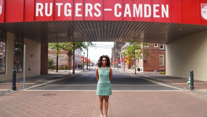 Student in green dress stands below the red Law Bridge sign