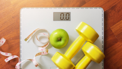 Photo of a scale, weights, an apple, and a measuring tape.