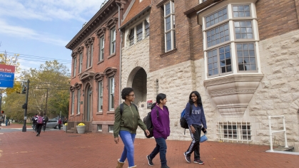 three female college students walking in front of Rutgers–Camden buildings
