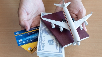 Hands holding airplane, cash, passport and credit cards