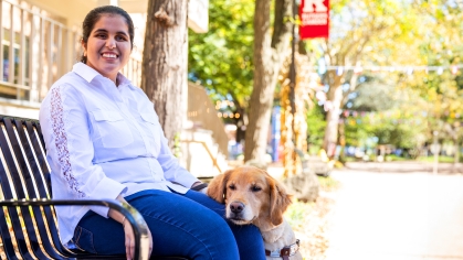 Kaur sitting on a bench with her service dog