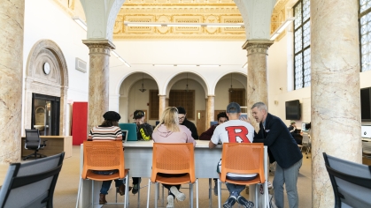 backs of students sitting under arch