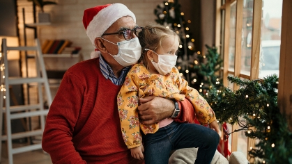 Santa with child sitting on lap with both wearing masks