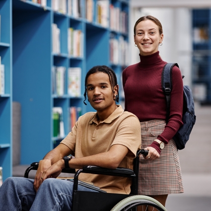 student pushing another student in wheelchair down the hall