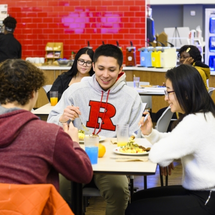male and female Rutgers–Camden students sitting at a table, eating in a dining hall
