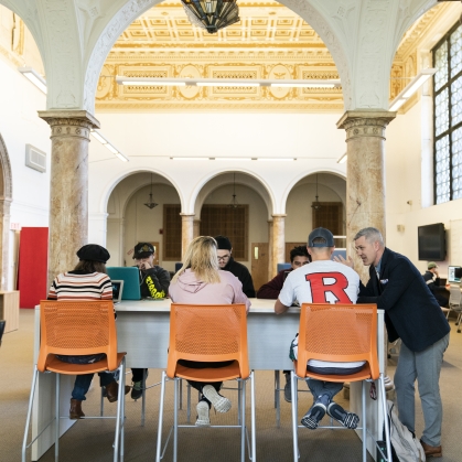 backs of students sitting under arch