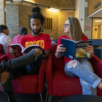 two students reading textbooks in lounge