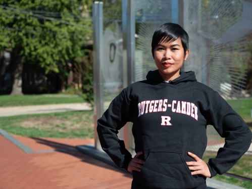 Asian student standing in front of outdoor sculpture