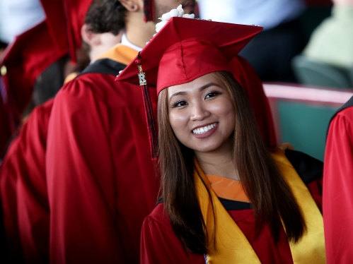 Student smiling in cap and gown at commencement
