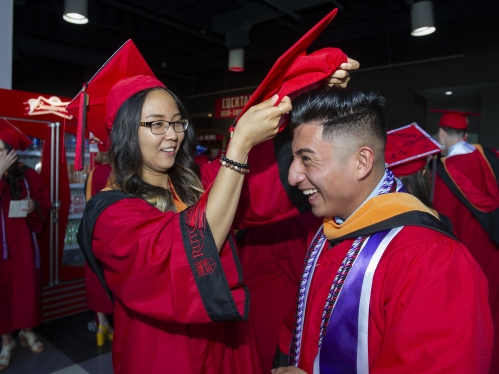 Student assisting other student by putting on his cap