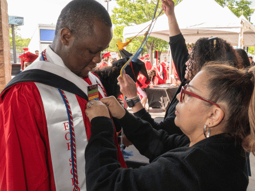 parent fixing graduate's graduation gown