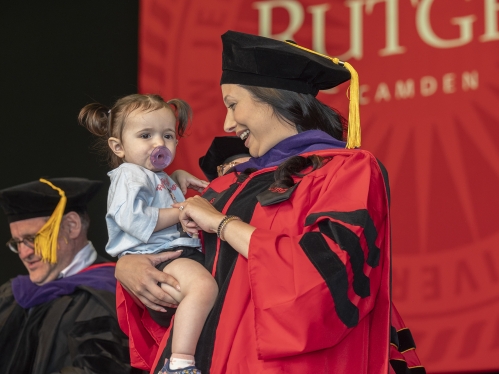 Law graduate about to receive diploma on stage carries small child with her