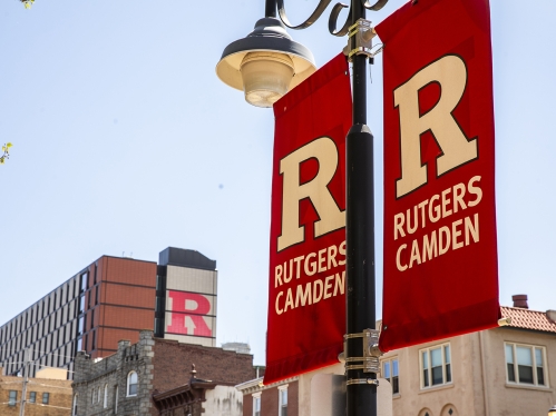 Rutgers Camden sign posts with the Student Housing building in the background.