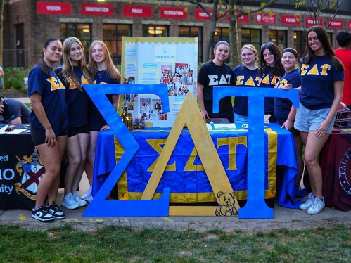 Sorority Sisters standing behind life-sized Greek symbols