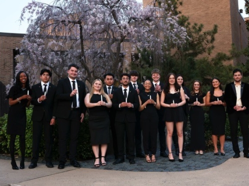 Order of Omega 1 gathered outside in formal dress holding candles