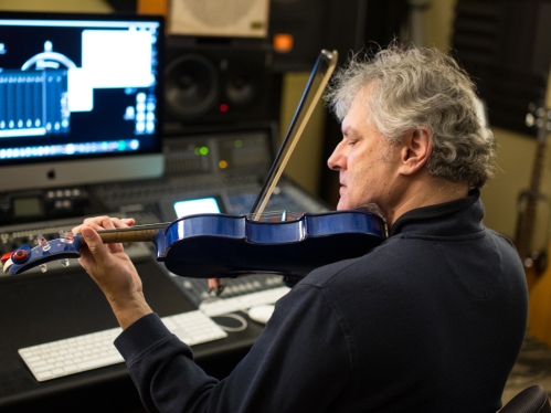 Professor in studio recording music from violin