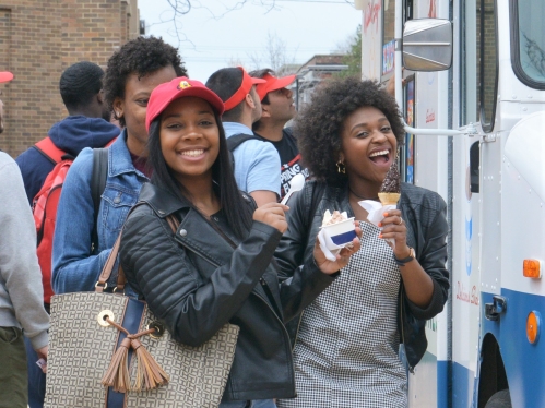students posing at ice cream truck holding ice cream