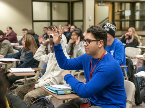 student raising hand during lecture