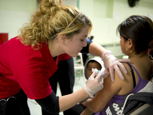 a female college nursing student inoculating a young woman in the arm