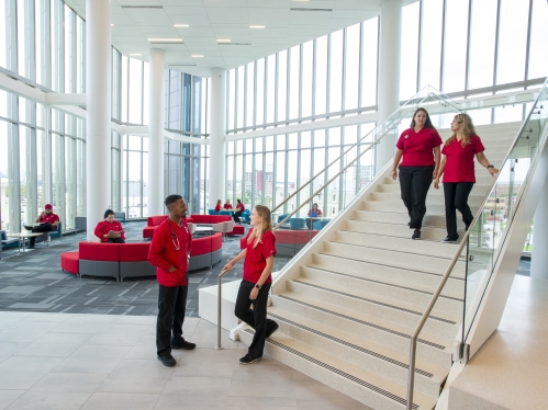 male and female college nursing students standing and walking and talking in a modern building lobby