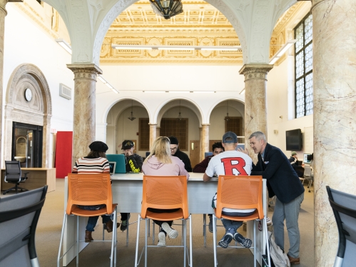 backs of students sitting under arch