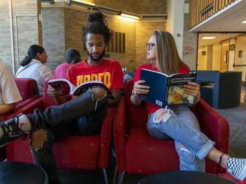 two students reading textbooks in lounge