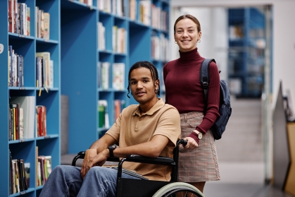 student pushing another student in wheelchair down the hall