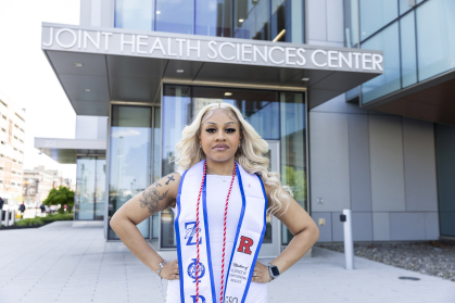 Student in white dress stands with hands on hips in front of Joint Health Sciences building