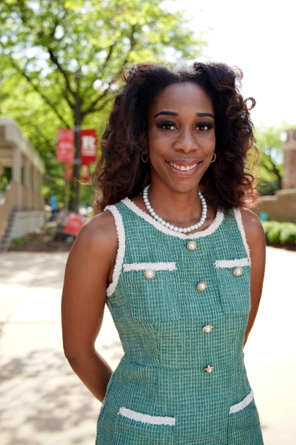 Student in green dress stands at in the campus quad