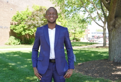 Student in blue suit stands on the quad near the Fine Arts Building