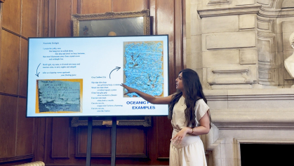 Student wearing an off-white outfit presents her work at a large screen