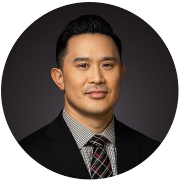Aaron Chang, the School of Business Commencement Speaker is seated for a formal portrait against a dark background.