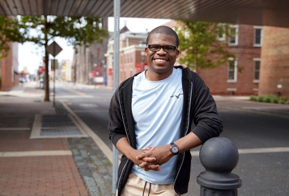 Alumnus stands and smiles along Fifth Street near the Law School Building.