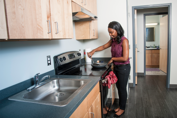 student in residence hall stirring pot on top of stove
