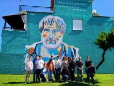 Greek wall mural of Aristotle with students in front.