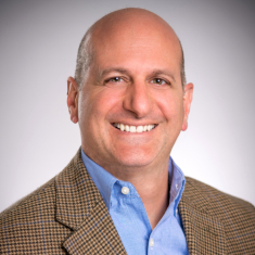 Headshot of smiling man with a blue shirt and brown blazer